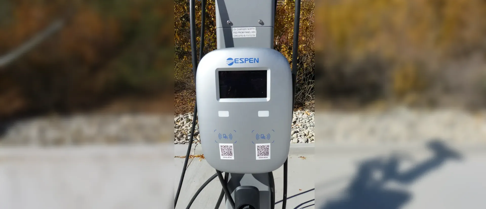 White utility meter mounted on a pole, with a digital display and cables against an outdoor background