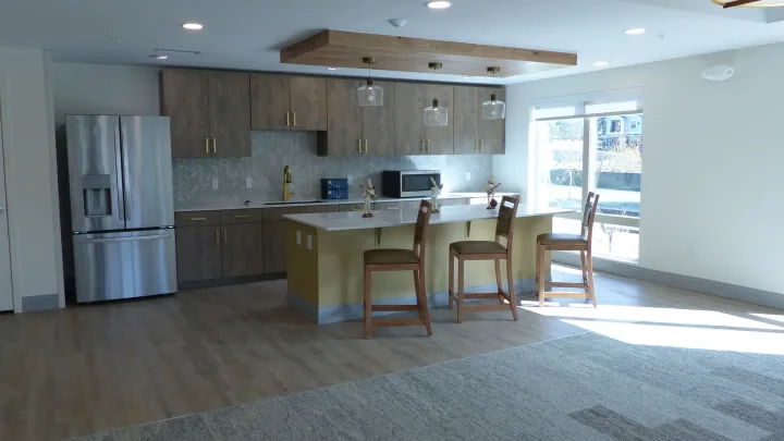 Bright kitchen and dining area with wood cabinets, island, and sunlight through large windows.