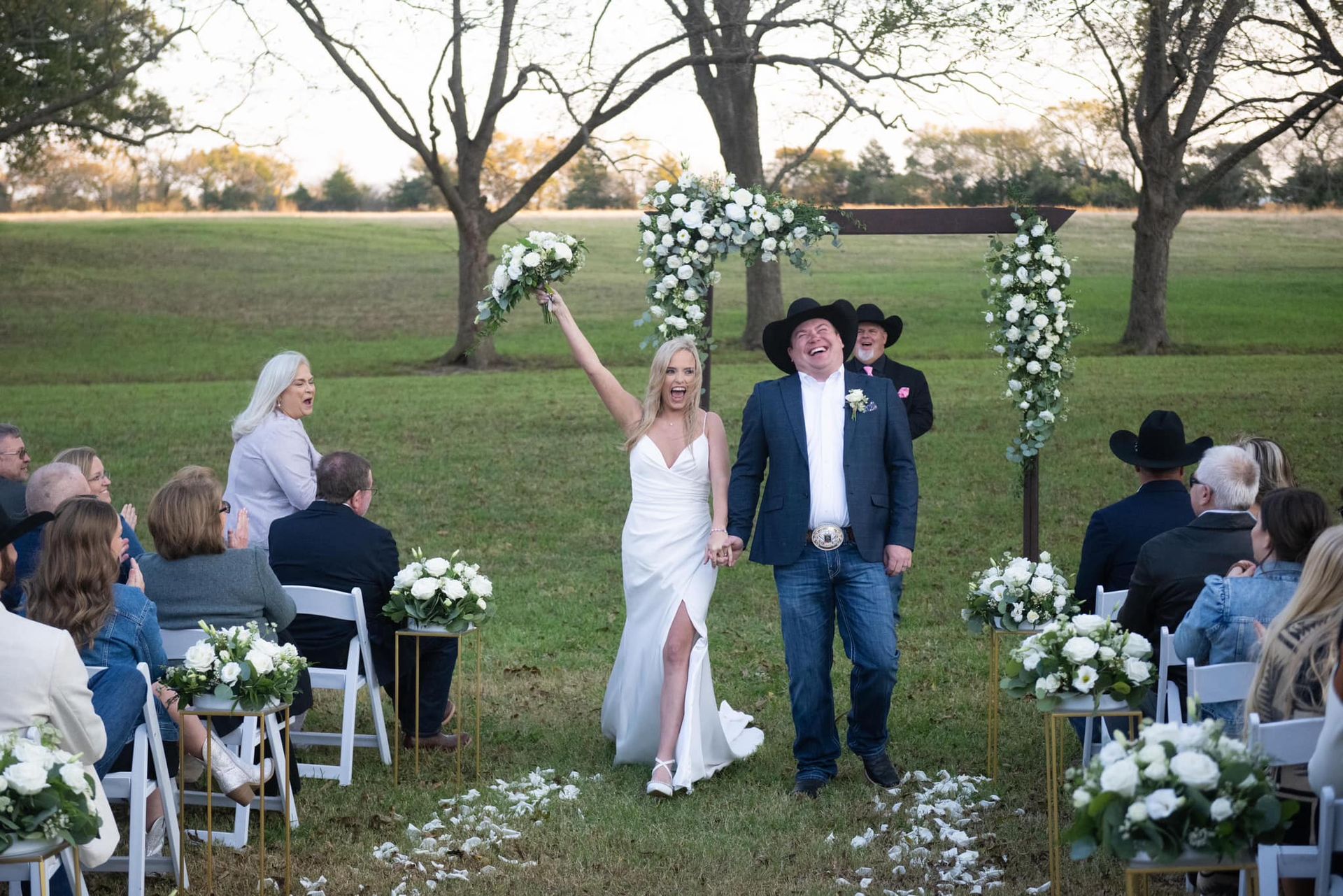 bride and groom cheering while walking down aisle in outdoor wedding ceremony
