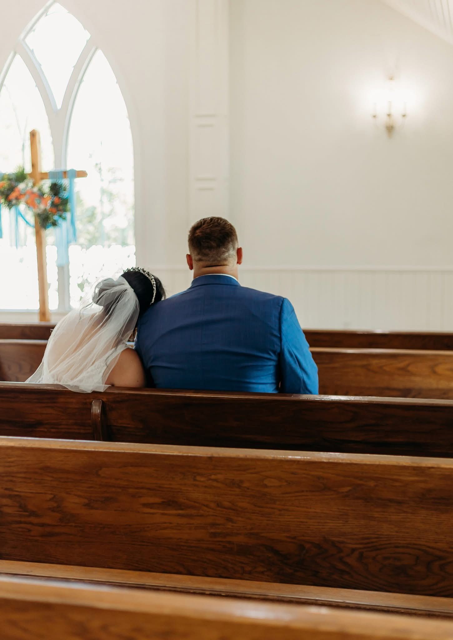 bride resting her head on groom's shoulder on church pew