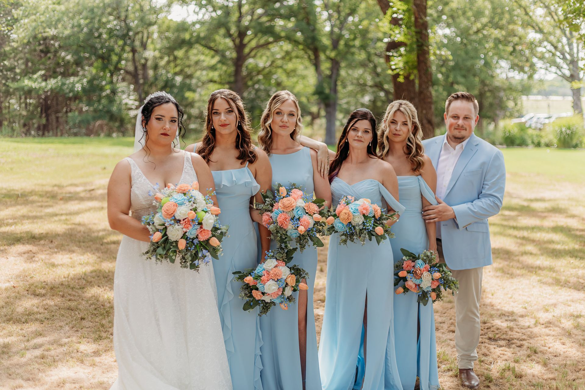 bride with bridesmaids in light blue gowns holding pink and blue bouquets