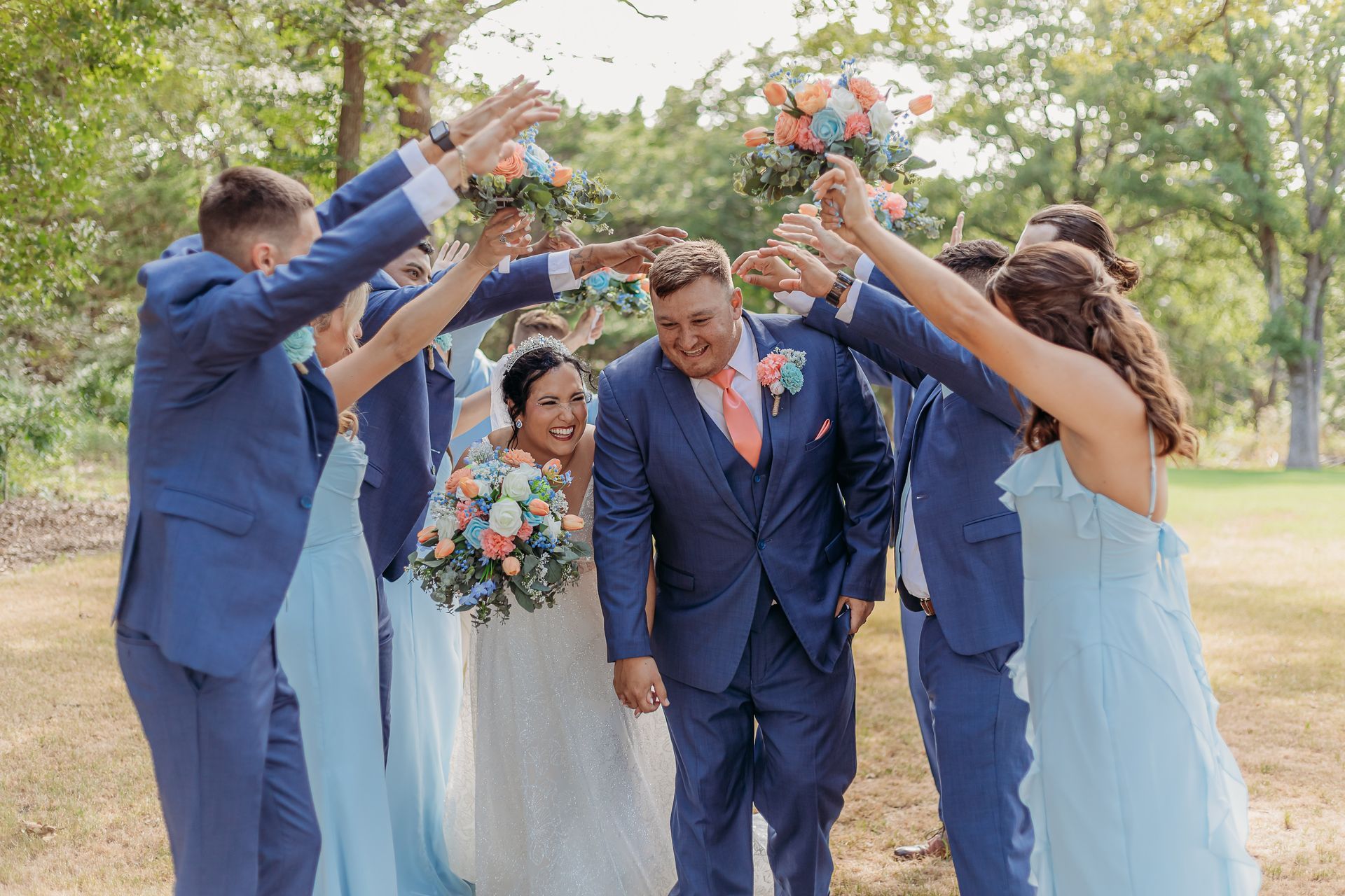 bride and groom walking between wedding party's arms