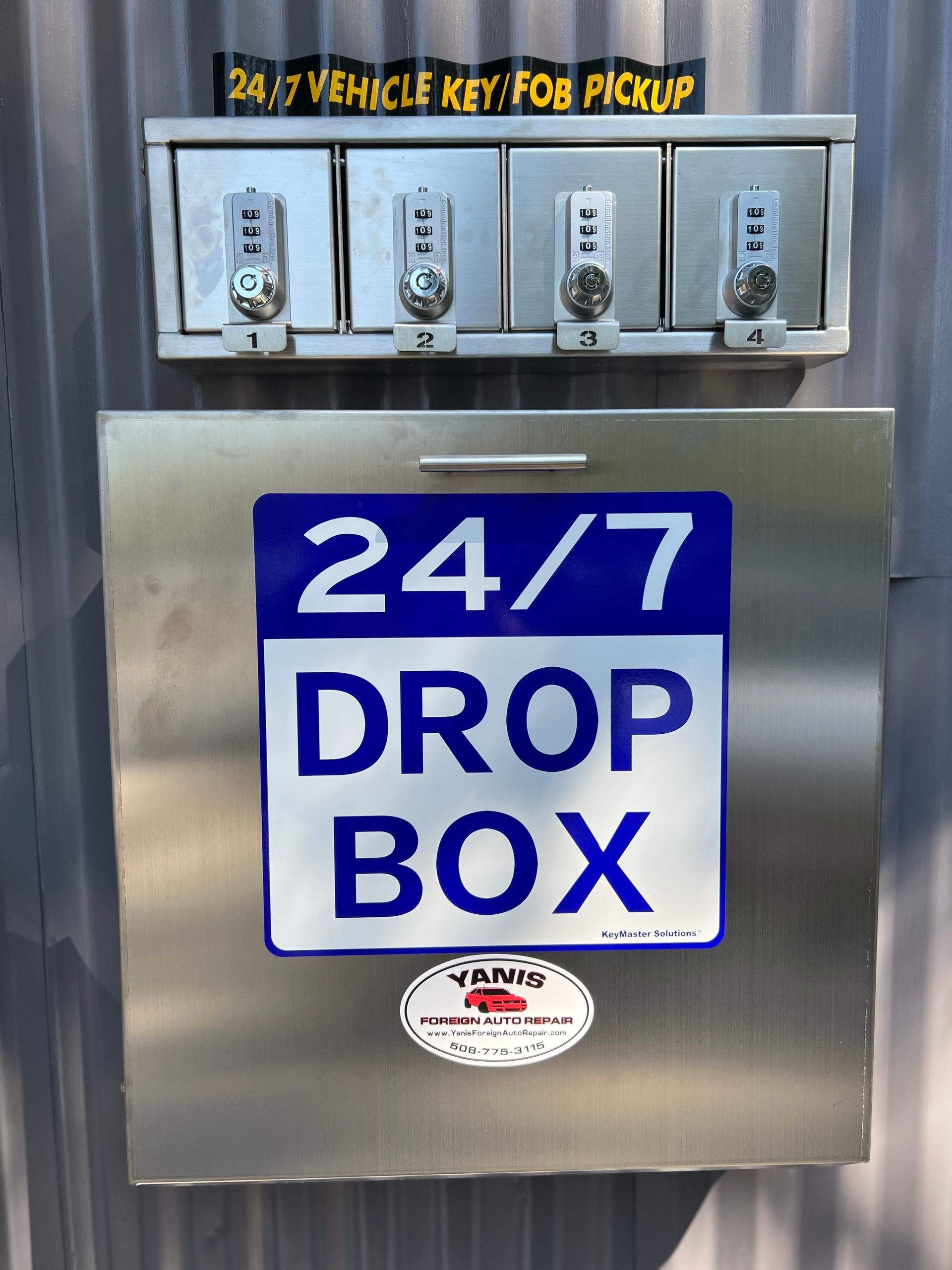 Metal 24/7 key and fob pickup with four combination locks, above a drop box.