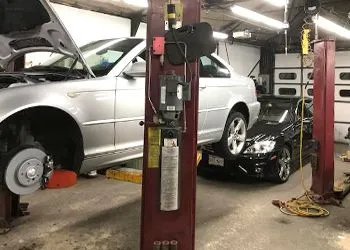 Two cars are sitting on a lift in a garage.