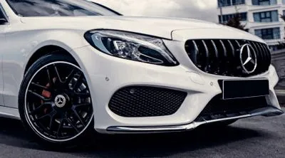 A white mercedes benz c class is parked on the side of the road.