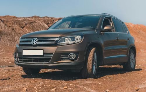 Dark gray Volkswagen SUV parked on a dirt road in a rocky desert landscape.