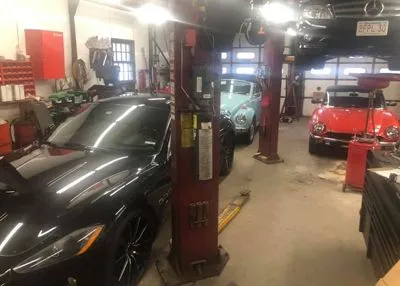 A couple of cars are parked in a garage.