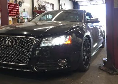 A black audi is parked in a garage on a lift.
