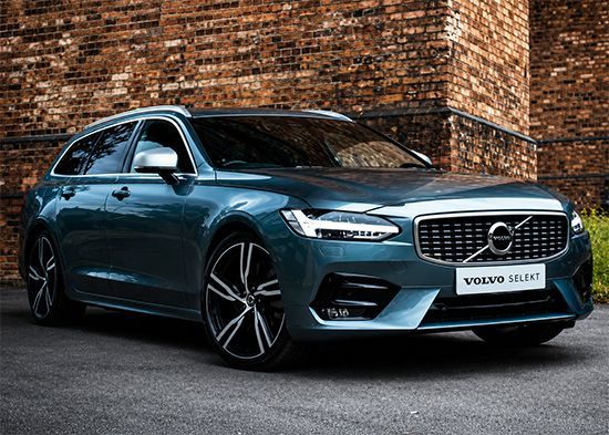 Blue Volvo station wagon parked by a brick wall on a street.