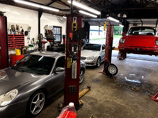 Auto repair shop with several cars, including a red car on a lift and a silver sports car in the foreground
