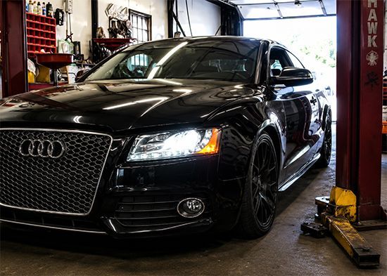 Black Audi sports car in a garage, front view with headlights on