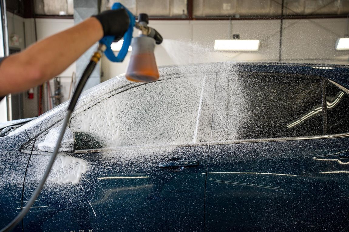 A person is washing a car with a foam sprayer.
