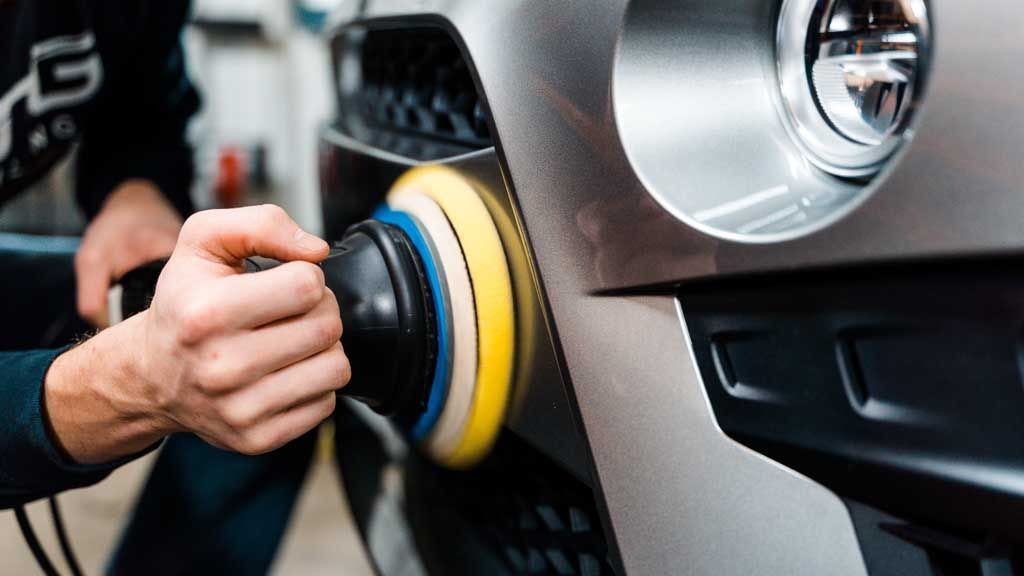 A man is polishing a car with a machine.