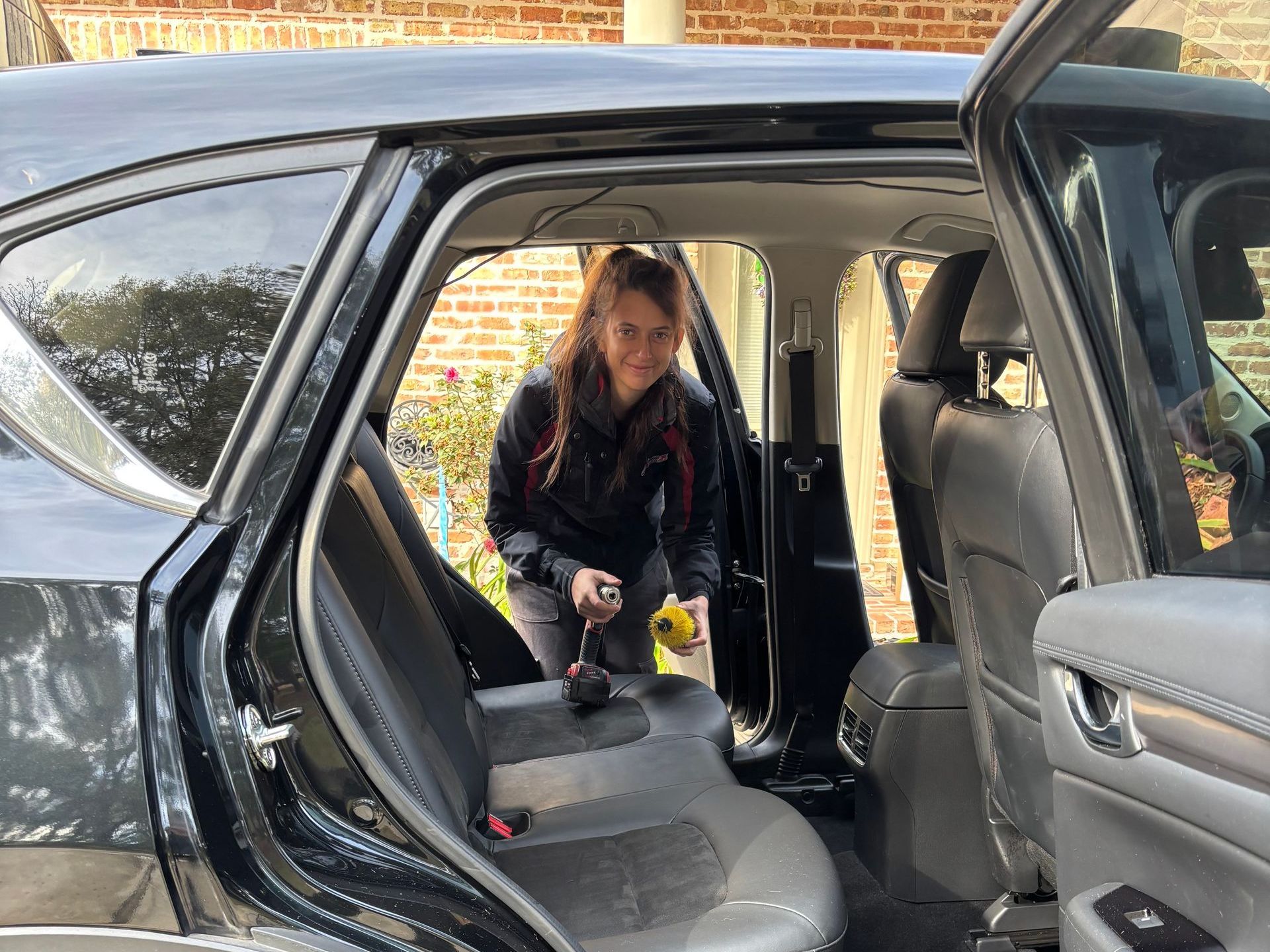 Child kneeling inside a black SUV, reaching across the back seat with the door open.