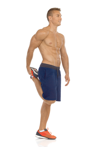 Man in blue shorts stretches his quad by pulling his foot towards his glutes.