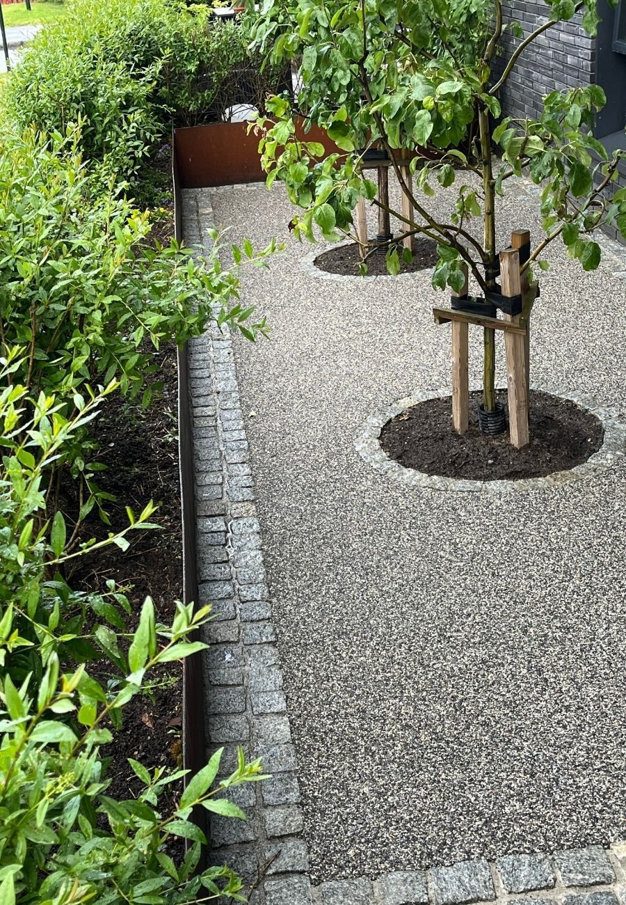 Gangsti med lyst resinbundet steindekke gjennom beplantning.