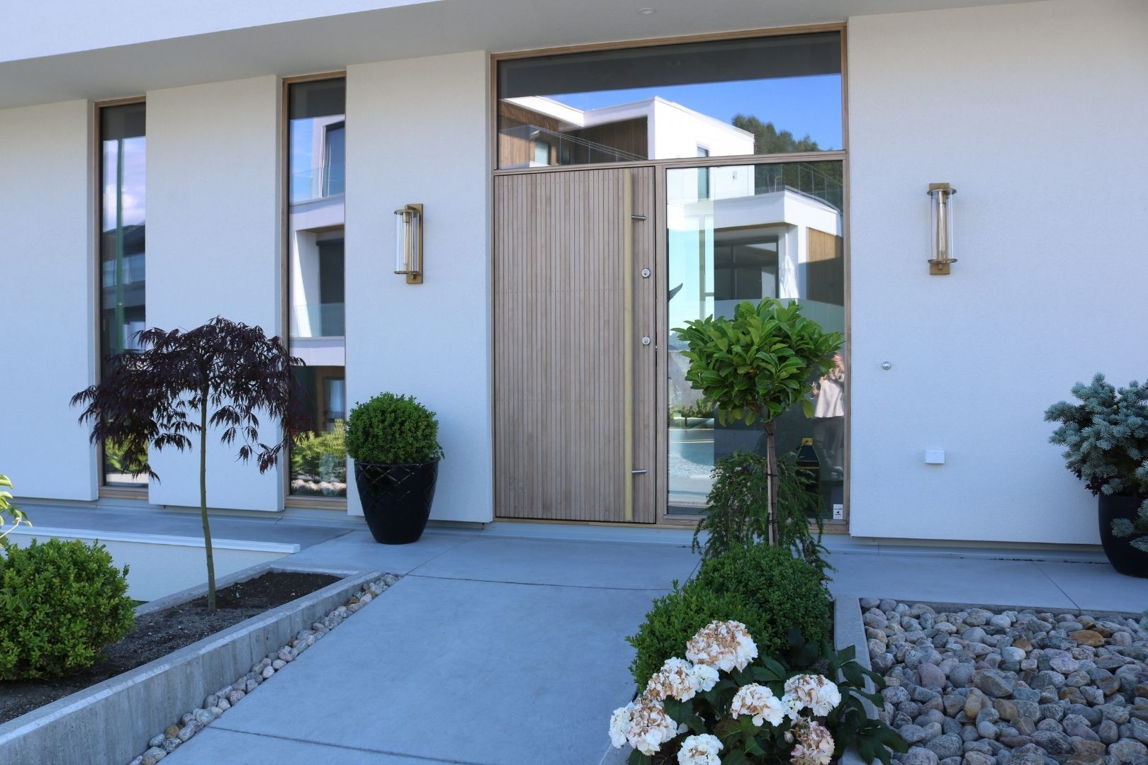 Moderne inngangsparti med plantekrukker og steinbed.
