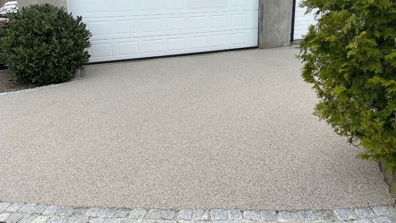 Lys innkjørsel med resinbundet steindekke foran garasje.