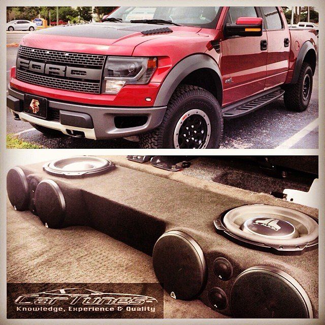 Red Ford Raptor truck with custom audio setup.