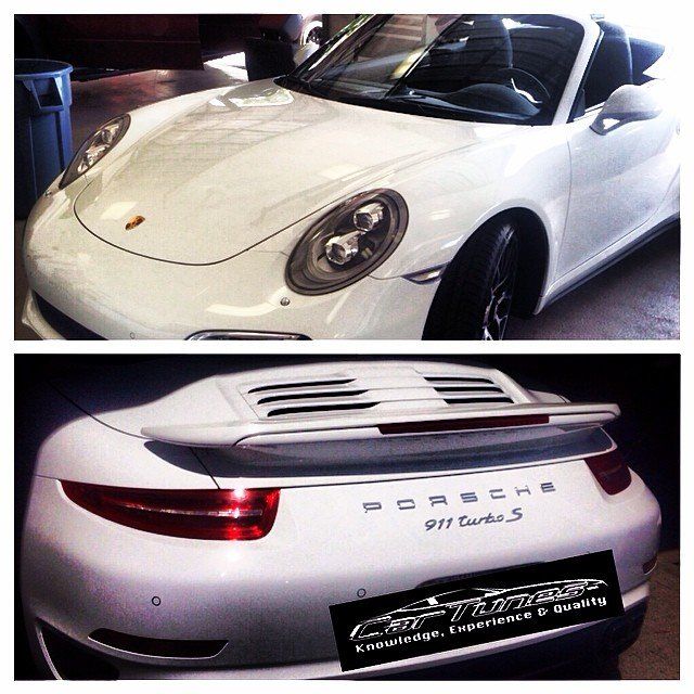 White Porsche 911 Turbo S, front and rear views, in a garage setting.