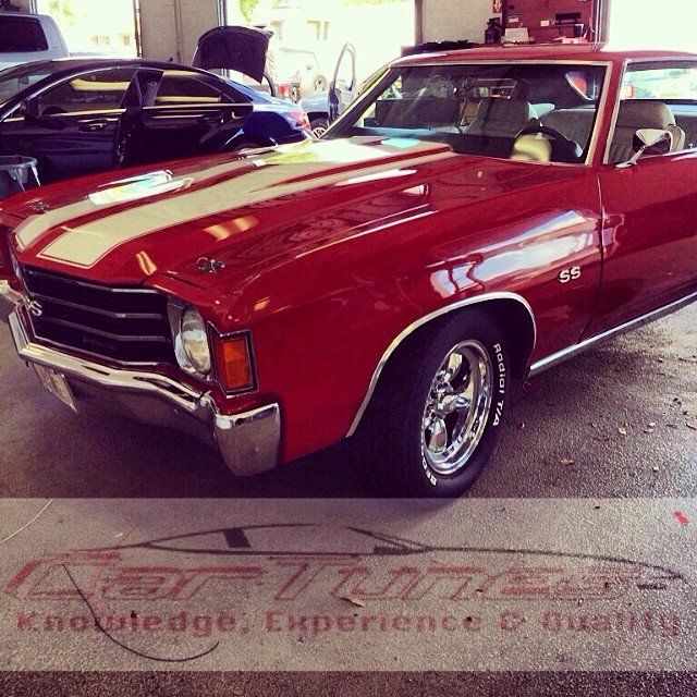Red classic car with white stripes, parked in a garage.