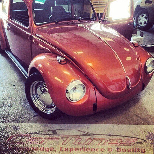 Orange classic Volkswagen Beetle car parked in a garage.