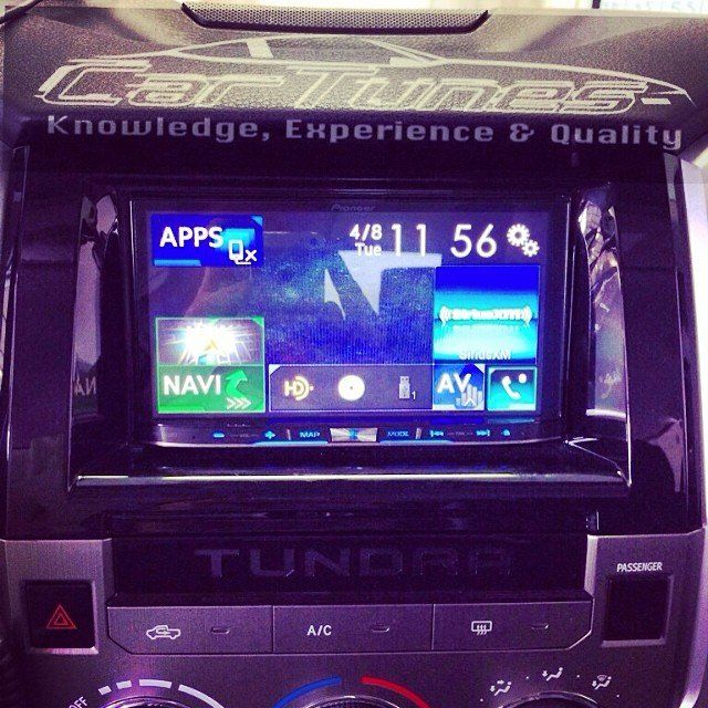 Car dashboard with a touchscreen display showing apps, navigation, and media controls. The car is a Toyota Tundra.