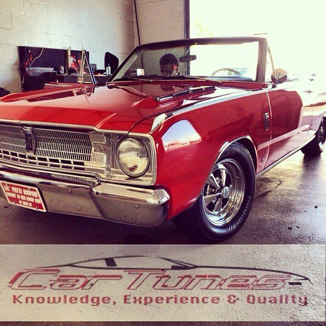 Red convertible car, parked inside a garage. A man is in the driver's seat.