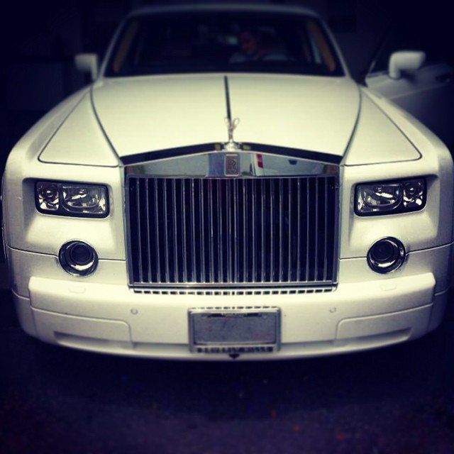 White Rolls Royce parked, front view, with silver grille and hood ornament.