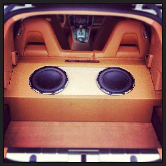 Tan car interior with two large speakers in a custom subwoofer enclosure.