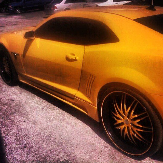 Yellow Chevrolet Camaro with black rims parked outside.
