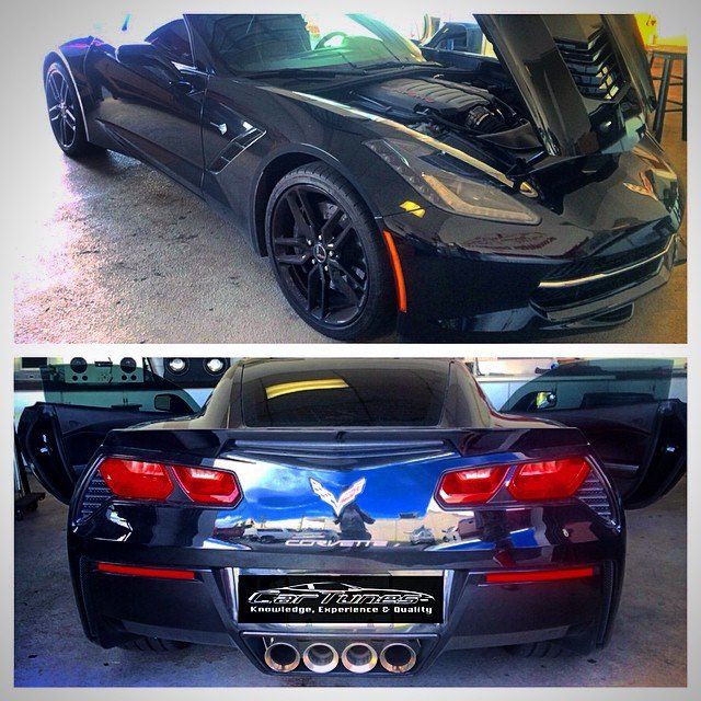 Black Corvette with open hood and doors, showcasing rear exhaust.