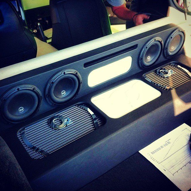 Car audio system: black and white speaker enclosure with multiple speakers and amplifiers installed.