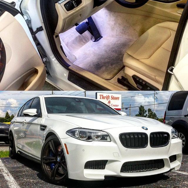 White BMW M5 with beige leather interior, parked in front of a thrift store.