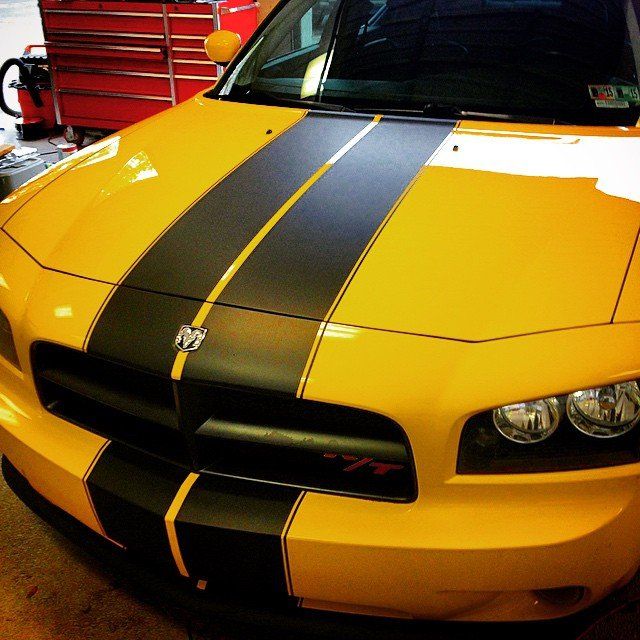 Yellow Dodge Charger with black racing stripes.