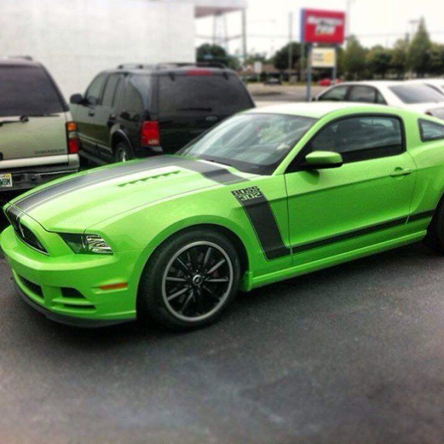 Green Ford Mustang Boss 302 with black stripes, parked in a lot.