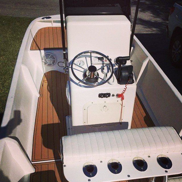 White boat interior with wood-look decking, center console, steering wheel, and seating.