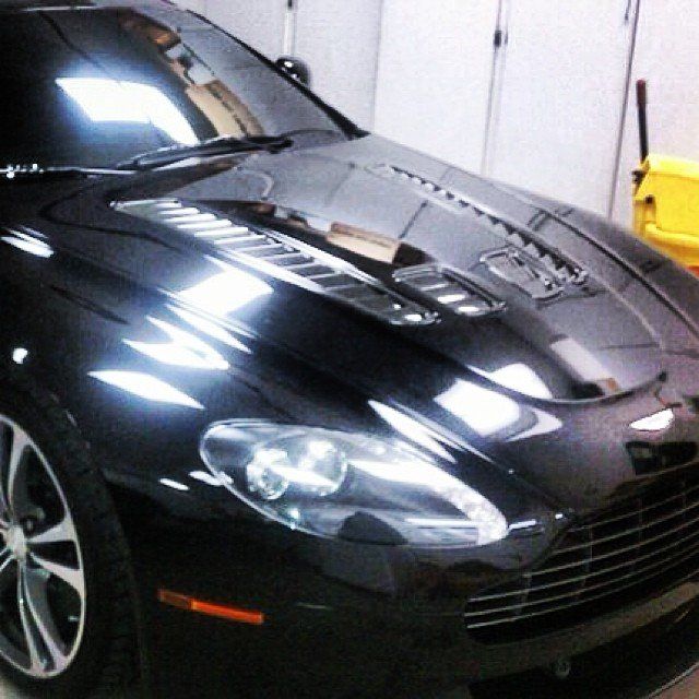 Black Aston Martin sports car, glossy finish, parked indoors.