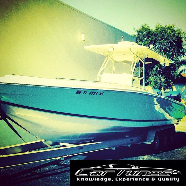 Boat on trailer, teal hull, white top, against a light green wall. Florida registration visible.