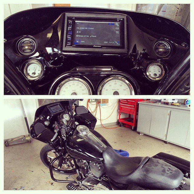 Black motorcycle with a Pioneer stereo system and gauges, inside a garage.