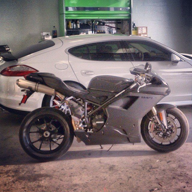 Gray motorcycle parked in a garage next to a white car.