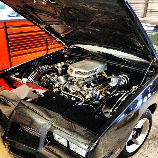 Black classic car with the hood open, showing engine details.