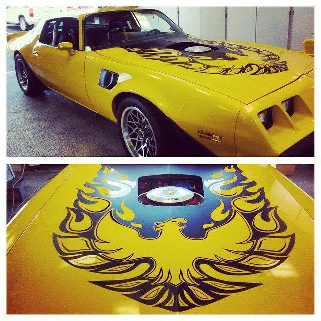 Yellow Pontiac Firebird with large black and gold phoenix hood decal.