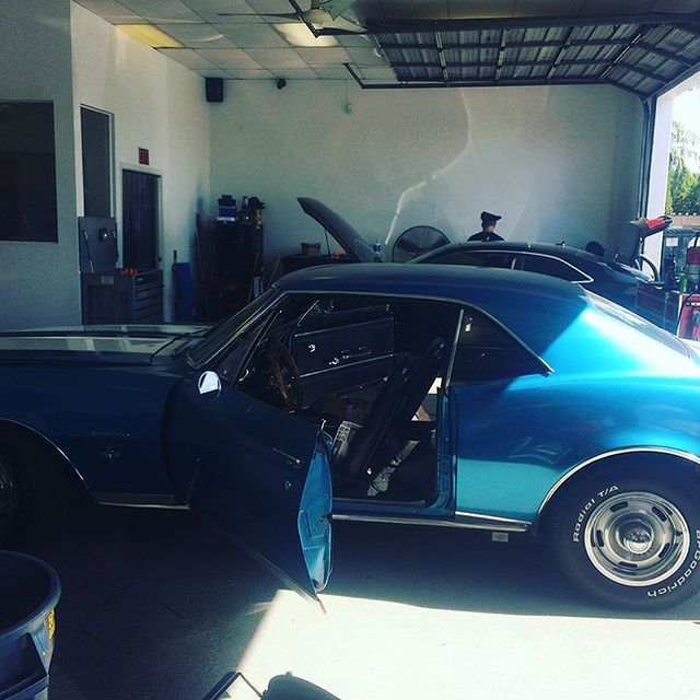 Blue classic car with open door in a garage.