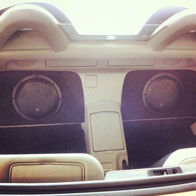 Interior of a convertible car with two large speakers installed in the back.