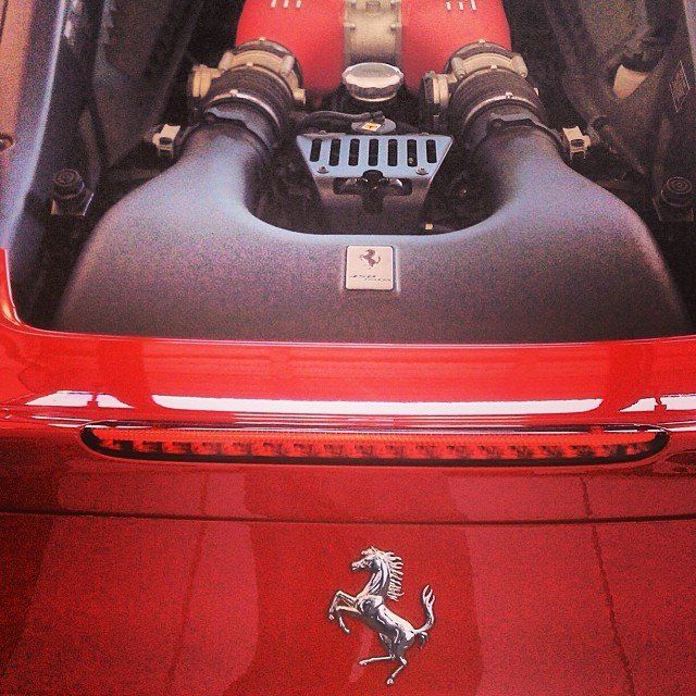 Red Ferrari engine with black air intakes and a silver emblem.