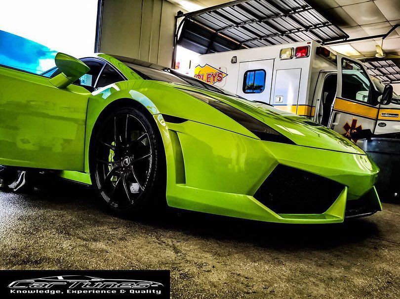 Lime green Lamborghini with open door, parked next to ambulance.