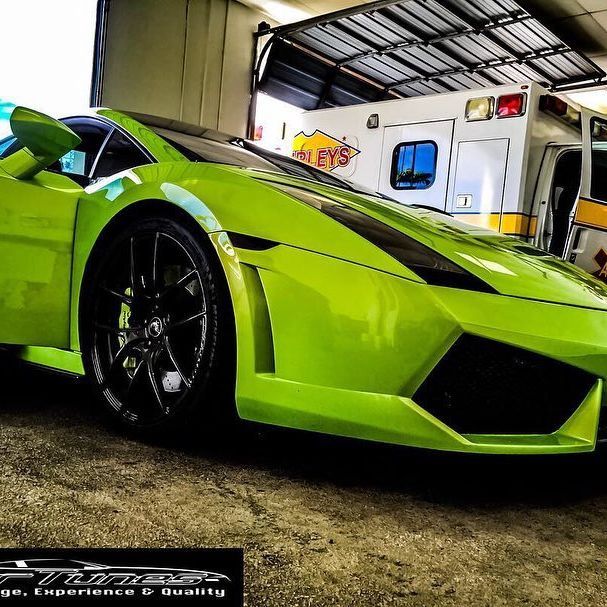 Green Lamborghini sports car parked next to an ambulance.