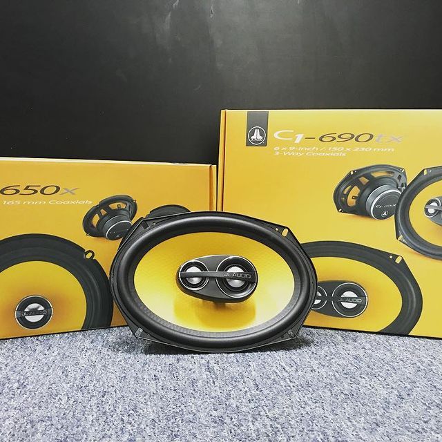 Oval car speakers with yellow cones and black surrounds, next to their boxes.