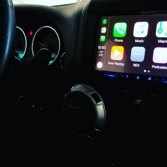 A car dashboard with a Pioneer touchscreen displaying Apple CarPlay apps, including phone, music, and maps.